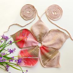 a crocheted bow and some flowers on a table