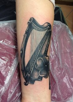 a tattoo on the arm of a woman with a black and grey harp in it