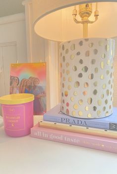 a table topped with books and a white lamp next to a pink cup filled with ice cream