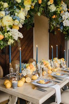 the table is set with lemons, blue candles and white flowers in front of it