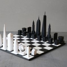 a black and white chess board with skyscrapers in the background on a gray surface