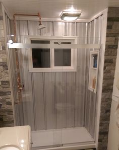 a bathroom with a walk in shower next to a white sink and toilet under a window