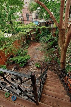 the stairs lead up to an apartment building and are surrounded by trees, bushes, and other greenery