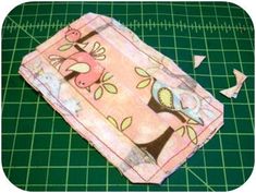 a pink cloth with birds on it sitting on a green cutting board next to scissors