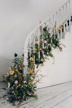 flowers are growing up the side of a white stair case in front of a door