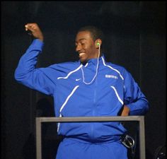 a man in blue is standing at a podium and raising his fist up to the crowd