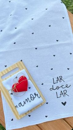 a wooden table topped with a red heart on top of a white cloth covered in writing