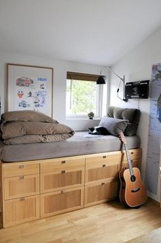 a bed room with a guitar and a cat laying on top of the bedspread