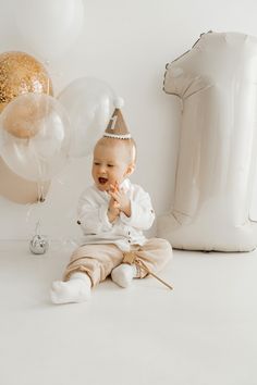 a baby sitting on the floor with balloons