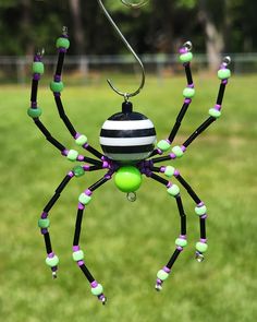 a black and white spider with green balls hanging from it's legs