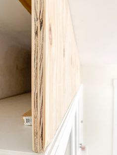 a close up of a wooden shelf in a room with white cupboards and drawers