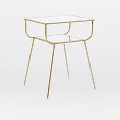 a glass and metal side table with gold legs