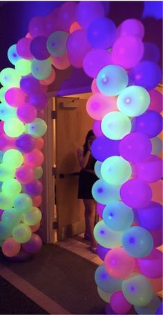 a woman taking a selfie in front of an archway with balloons hanging from it