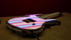 an illuminated guitar sitting on top of a wooden table