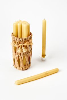 a wicker basket filled with candles next to a candle holder and yellow pencils