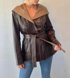 "Sourced from a high end leather & fur shop in Turkey, this hooded jacket is truly unique. Extremely soft dark brown leather with satin printed lining. This beautiful piece features two side pockets, detail stitching, slim shoulder pads, button down front and a waist tie belt. Oversize hooded collar with plaid fabric. Condition is excellent with no flaws to mention. Label: Emelda  Size: women's US 10 or Turkey size 40 Fit: best fits size Small-Medium  *Model is 5'7\" size small or US 2 for reference.  Shoulder to shoulder: 17\" Shoulder to hem: 27\" Sleeve length: 25.5\" Armpit to armpit: 20\"" Fall Hooded Leather Jacket With Padded Collar, Fitted Leather Hooded Jacket For Fall, Leather Jacket With Detachable Hood For Fall, Fitted Leather Hooded Jacket With Double-lined Hood, Fall Leather Jacket With Detachable Hood, Fitted Leather Outerwear With Double-lined Hood, Brown Hooded Leather Jacket With Detachable Hood, Brown Leather Jacket With Padded Collar For Winter, Brown Leather Jacket With Detachable Hood