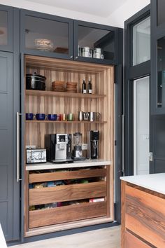 an open cabinet with many items on it in a kitchen next to a counter top