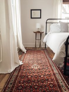 a bed sitting next to a window in a bedroom on top of a wooden floor