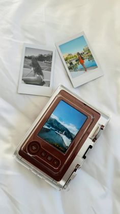 an old video game sitting on top of a white bed next to two polaroid pictures