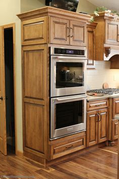 a kitchen with wooden cabinets and stainless steel ovens in the center, along with hardwood flooring