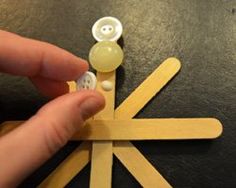 a person holding a pair of wooden clothes pins with buttons on them in front of a black table