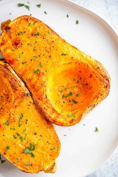 two baked sweet potatoes on a white plate with parsley sprinkled on top