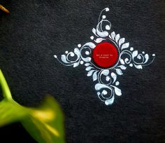 a close up of a red button on a black cloth with white designs and flowers