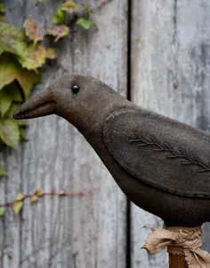 a bird statue sitting on top of a wooden pole next to a wall covered in ivy