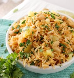 a white bowl filled with rice and veggies next to cilantro on a blue towel