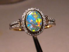 Solid 14 k Yellow Gold Ring inlaid with one Natural Australian Opal    surrounded by Natural Diamonds.    This Opal is from Lightning Ridge Australia. It is 100% Natural   and not a doublet or a triplet.   OPAL WEIGHT:  .80 carat OPAL SIZE:  7.5 x 5.5 x 1.5 mm COLORS:   Orange Blue Yellow Green QUALITY:  Flawless  BRIGHTNESS:  5 PATTERN:  Patch / Roll BODY TONE:   N-2 inlay GOLD WEIGHT:  4 grams solid 14k Yellow Gold SETTING:  11.4 mm across on the top deck north to south DIAMONDS:  50 Round Bri Heirloom Multicolor Oval Jewelry, Elegant Multicolor Opal Ring, Formal Multicolor Opal Ring, Multicolor Oval Halo Setting Jewelry, Oval Multicolor Jewelry With Halo Setting, Multicolor Oval Jewelry With Halo Setting, Multicolor Oval Opal Ring For Formal Occasions, Multicolor Round Jewelry With Halo Setting, Multicolor Jewelry With Halo Setting