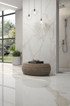 a bathroom with marble walls and flooring next to a large glass window that looks out onto the outdoors