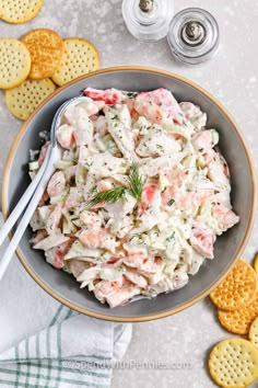 a bowl filled with crab salad next to crackers