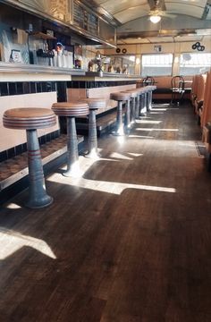 the inside of a restaurant with wooden tables and stools