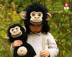 a young child wearing a knitted monkey hat and holding two stuffed monkeys in their arms