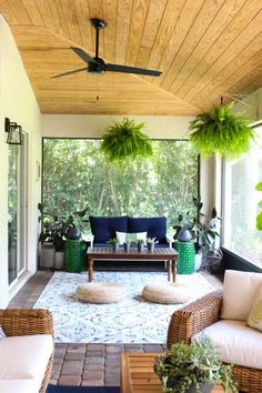 an outdoor living area with wicker furniture and potted plants on the porch ceiling