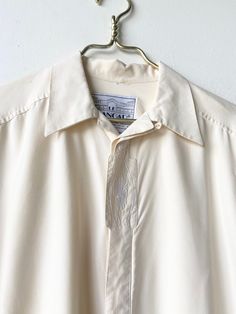 A 1970s men's dress shirt in a creamy silk with embroidered design on portion of button down strip. In amazing vintage condition with no rips tears or stains. Mens drrss shirt but definitely be considered unisex Bust 50 length24.5 sleeve 23 Shoulder 9.5 Beige Formal Shirt For Summer, Beige Formal Summer Shirt, Collared Dress Shirt For Summer Daywear, Summer Daywear Collared Dress Shirt, Collared Summer Dress Shirt For Daywear, Summer Collared Dress Shirt For Daywear, Cream Formal Shirt With Spread Collar, Cream Spread Collar Shirt For Spring, Formal Cream Shirt With Spread Collar