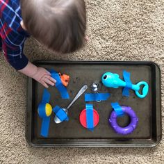 a toddler playing with toys on the floor in front of him and his tray