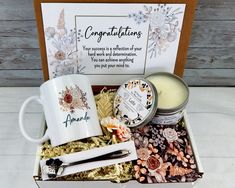 a gift box containing two mugs, some candles and other personal care items in it