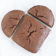 four slices of chocolate cake sitting on top of white paper with holes in the middle