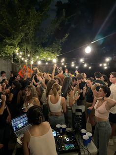 a group of people standing around each other in front of a dj booth at night