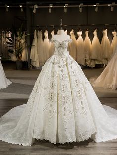 a wedding dress on display in a bridal room with other gowns behind it