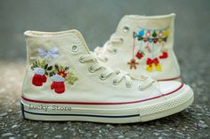 a pair of white shoes with embroidered bows on them