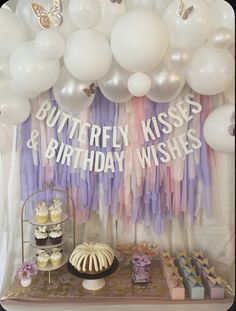 a table with cake, cupcakes and balloons in the shape of butterfly kisses