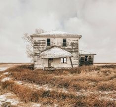 an old run down house sitting in the middle of a field with no grass on it