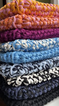 a stack of knitted blankets sitting on top of a table