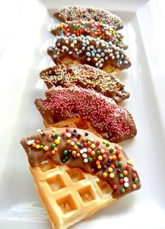 three waffles with chocolate and sprinkles on them sitting on a white plate