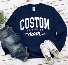 "Custom University Mom Sweatshirt, Cool Cozy University Mom Gift Sweater, Proud Mom Crewneck , standard USA size men's women's available in 6 color ; Black, White, Navy, Sport Grey, Irish Green and Red. This Sweatshirt using USA standard size; S, M, L, XL, 2XL, 3XL. Sweatshirt Spec's Using Direct to Garment (DtG) for quality and durability print. * 8 oz./yd² (US) 13.3 oz./L yd (CA), 50/50 preshrunk cotton/polyester * Classic fit * Air jet yarn for softer feel and reduced pilling * Double-needle stitching at shoulders, armholes, neck, waistband and cuffs * 1x1 rib with spandex for enhanced stretch and recovery Size Chart * SMALL (W 20\" / L 27\" / SLEEVE 33.5\") * MEDIUM (W 22\" / L 28\" / SLEEVE 34.5\") * LARGE (W 24\" / L 29\" / SLEEVE 35.5\") * X-LARGE (W 26\" / L 30\" / SLEEVE  36.5\") Relaxed Fit Lettering Tops For Campus, Relaxed Fit Long Sleeve T-shirt For Campus, Long Sleeve Relaxed Fit T-shirt For Campus, Long Sleeve Letter Print Campus T-shirt, Long Sleeve Letter Print T-shirt For Campus, Long Sleeve Tops With Lettering For Campus, Varsity Long Sleeve T-shirt With Lettering, Cotton Campus Tops With Team Name, University Sweater