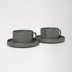 two gray cups and saucers on a white table