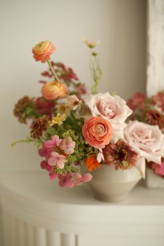 a white vase filled with lots of flowers on top of a table