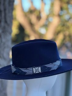 Designer choice!! Take a look at this fun denim blue adjustable hatband with different colors of denim that really make this hatband pop on any style/color of hat. The band is 22.5" x 1.25" and has adjustable navy-blue suede ties in the back so it can fit hats from 22.5-34". The band is secured by two gold tie clamps in the back to give it a nice, finished look. The hat band has been sewn together and treated with fray protector to help keep this hatband looking good for years to come. To comple Casual Adjustable Felt Hat For Country Events, Adjustable Casual Felt Hat For Kentucky Derby, Adjustable Casual Felt Hat With Flat Crown, Blue Short Brim Felt Hat For Fall, Blue Adjustable Fedora For Kentucky Derby, Blue Country Hat With Short Brim, Adjustable Navy Wide Brim Hat, Casual Blue Hats For Rodeo, Blue Fedora With Short Brim For Fall